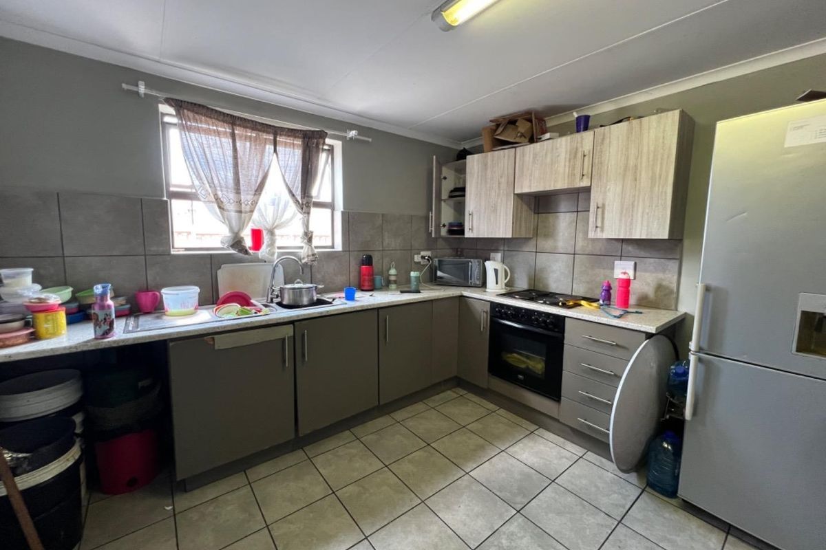 A functional kitchen featuring built-in cabinetry, laminate countertops, a built-in oven with hob, and tiled flooring with a tiled backsplash.