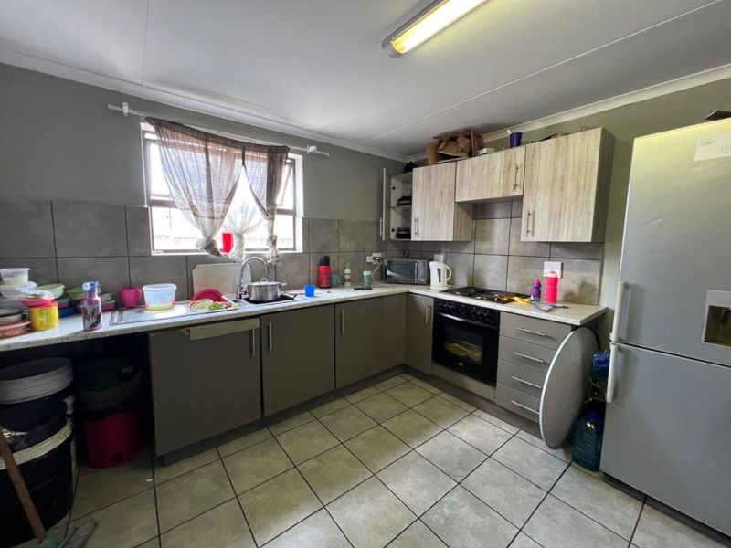 A functional kitchen featuring built-in cabinetry, laminate countertops, a built-in oven with hob, and tiled flooring with a tiled backsplash.