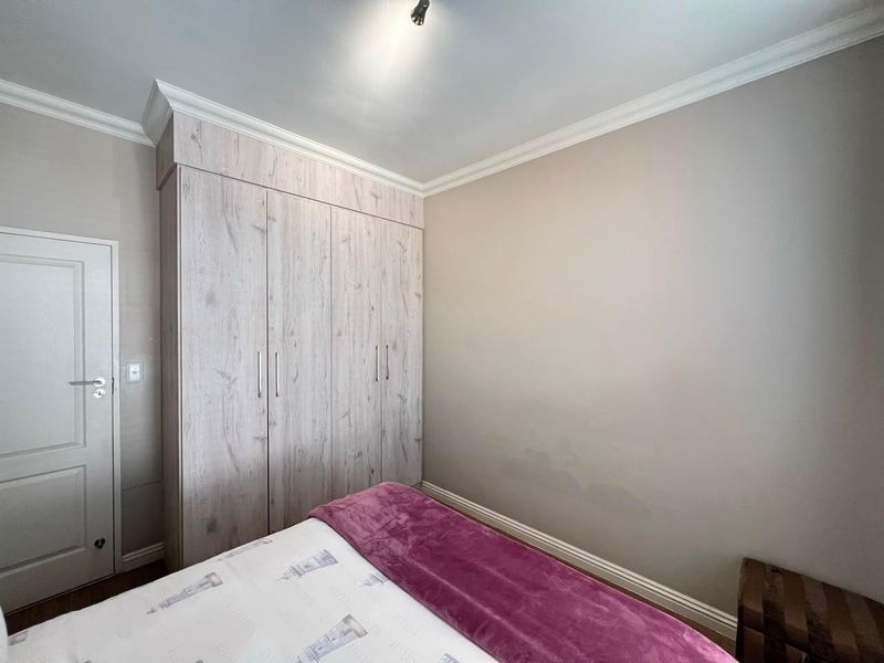 A bedroom featuring light wood-finish built-in wardrobes, crown molding, and neutral wall tones.