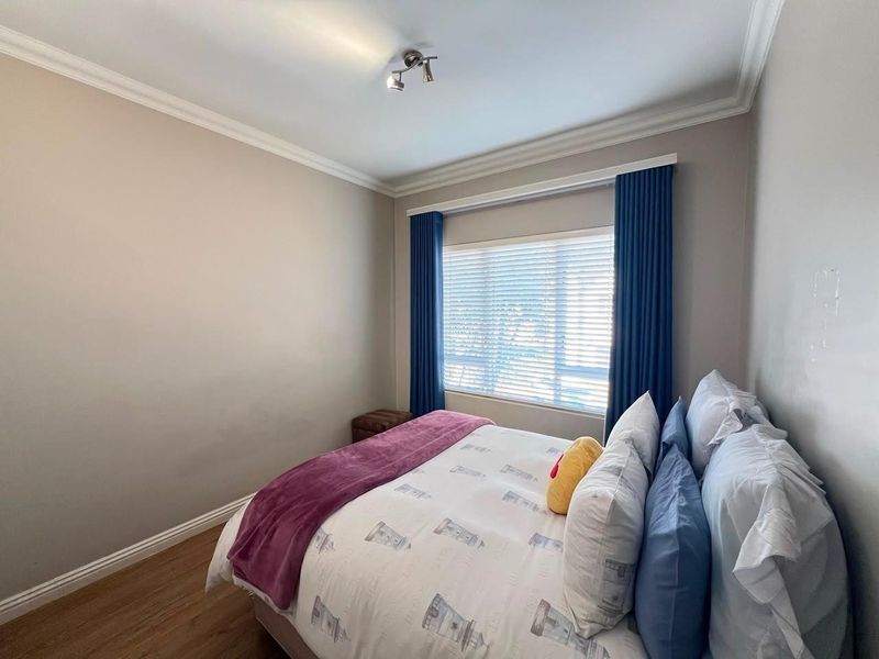 A well-maintained bedroom featuring laminate flooring, neutral wall tones, and a ceiling-mounted spotlight fixture.