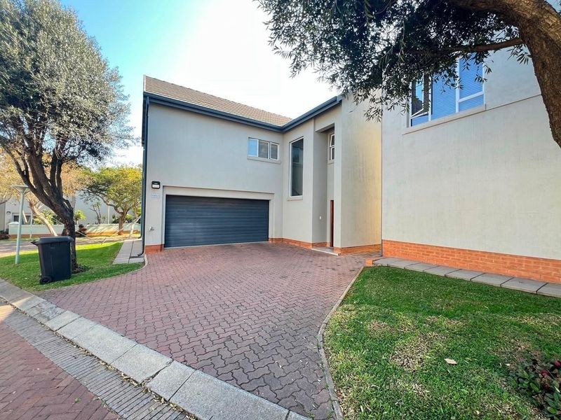 Front view of a modern house featuring a paved driveway, double garage, and well-maintained garden area.