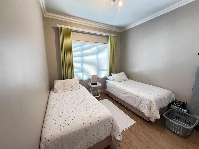 A well-maintained bedroom featuring laminate flooring, decorative cornicing, and venetian blinds, providing a clean and functional living space.