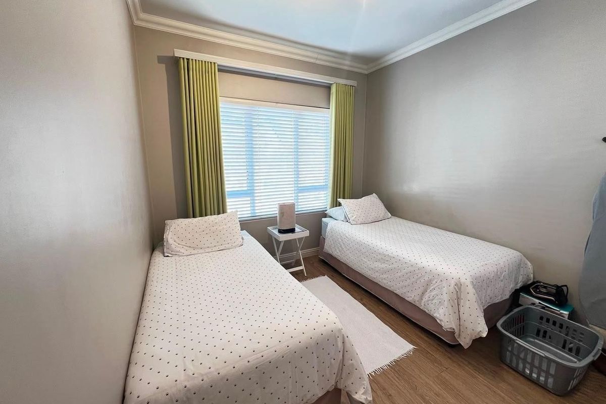 A well-maintained bedroom featuring laminate flooring, decorative cornicing, and venetian blinds, providing a clean and functional living space.