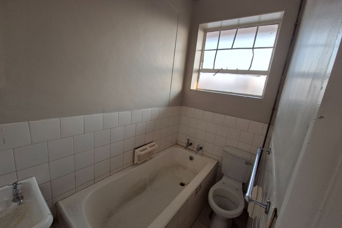 A dated bathroom featuring a bathtub, toilet, and pedestal basin, requiring cosmetic updates and maintenance to improve its overall condition.