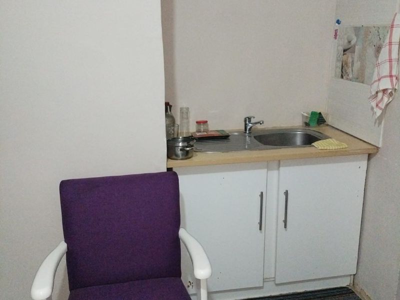 A compact scullery or utility area featuring a small stainless steel sink, base cabinetry, and tiled flooring, requiring minor finishing to the surrounding walls.