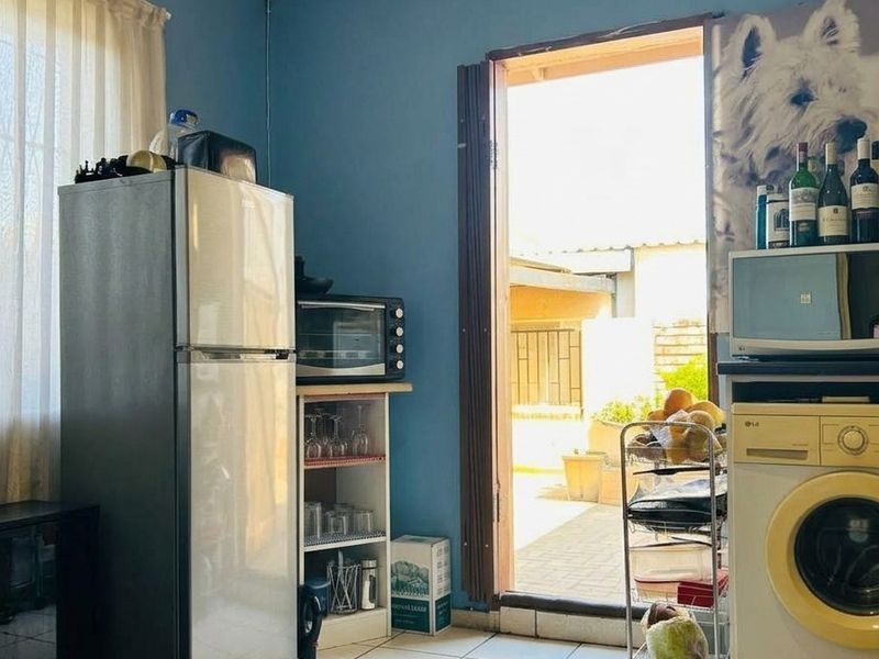 A functional laundry area featuring tiled flooring and direct access to an outdoor patio space.