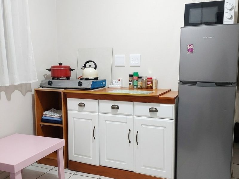 A compact kitchen area featuring white cabinetry, tiled flooring, and a functional counter space for food preparation.