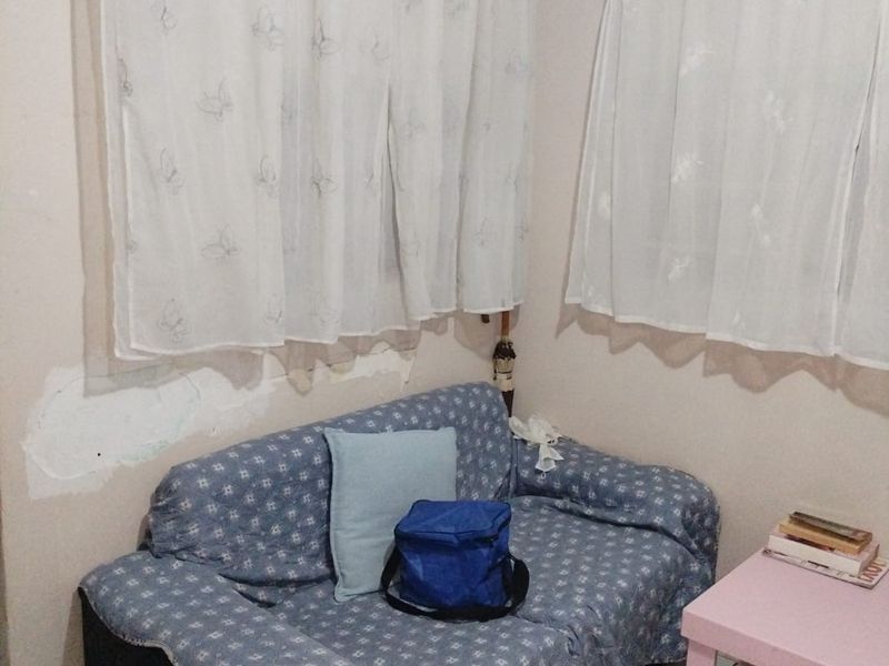 A small living area featuring tiled flooring and cove cornicing, currently showing visible wall plaster damage and peeling paint.