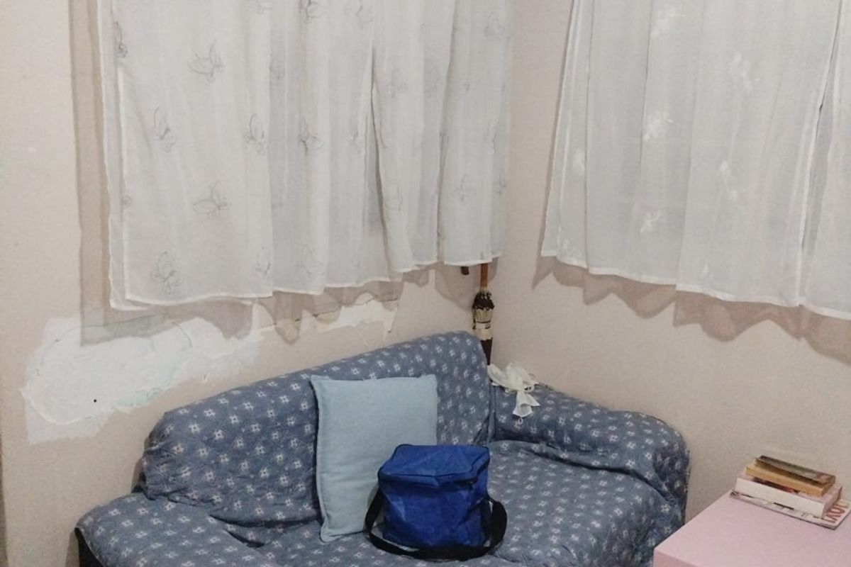 A small living area featuring tiled flooring and cove cornicing, currently showing visible wall plaster damage and peeling paint.