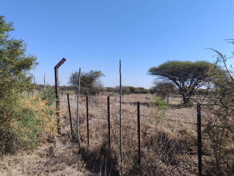 A view of the vacant residential land featuring dry vegetation and existing wire perimeter fencing with weathered metal posts.