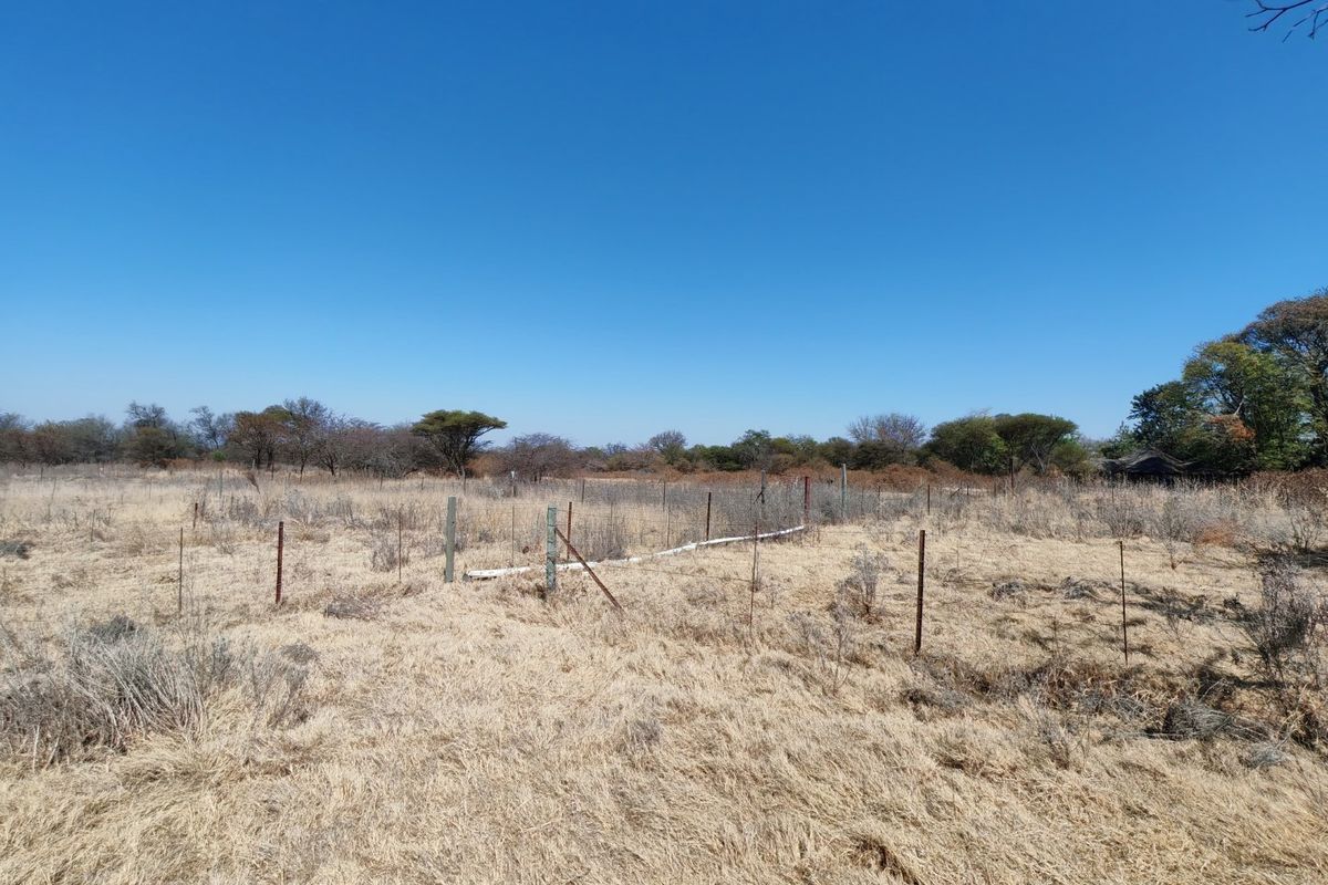 A view of a vacant residential plot featuring dry vegetation and existing wire perimeter fencing.
