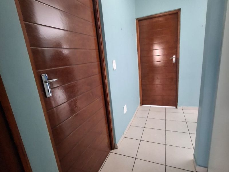 A clean, well-maintained hallway featuring light-colored floor tiles and two polished wooden doors.