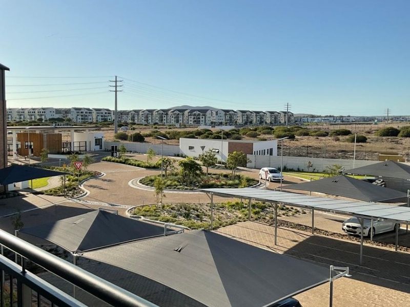 Elevated view overlooking the apartment complex grounds, featuring paved driveways, landscaped traffic circles, and covered parking bays.