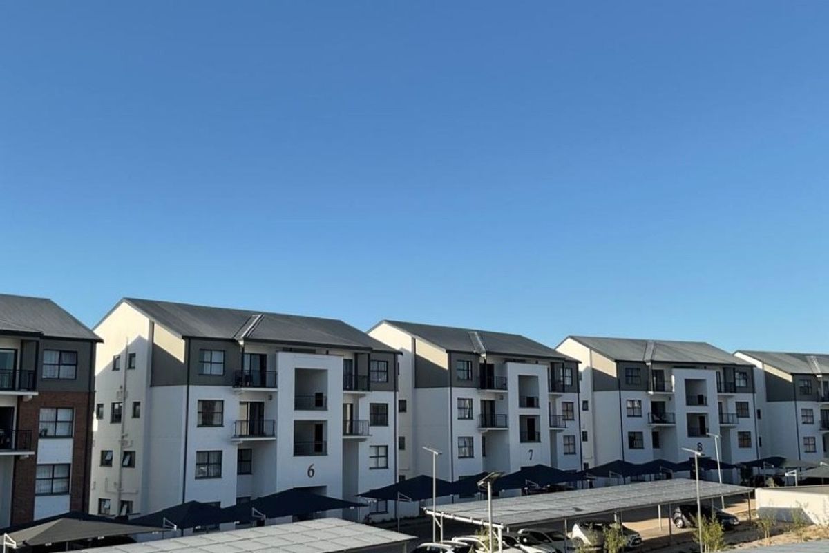 An elevated view of a modern apartment complex featuring covered parking bays and private balconies.