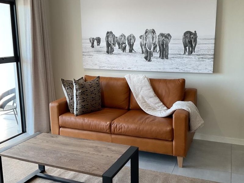 A well-maintained living room featuring neutral tiled flooring and a large sliding glass door providing natural light and access to the outdoor area.