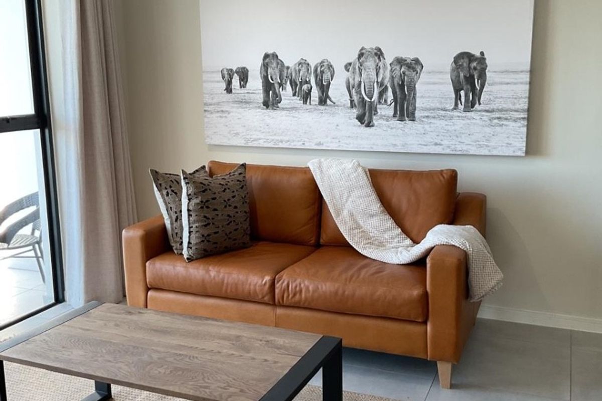 A well-maintained living room featuring neutral tiled flooring and a large sliding glass door providing natural light and access to the outdoor area.
