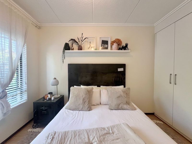 A well-maintained bedroom featuring a built-in wardrobe, neutral wall finishes, and venetian blinds, providing a clean and functional living space.
