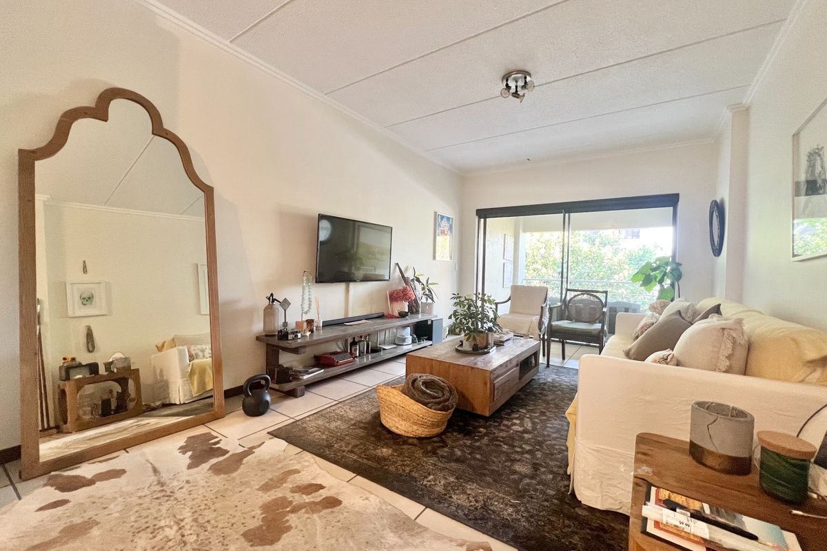 A bright living room featuring tiled flooring and a large sliding glass door that provides access to an outdoor balcony area.