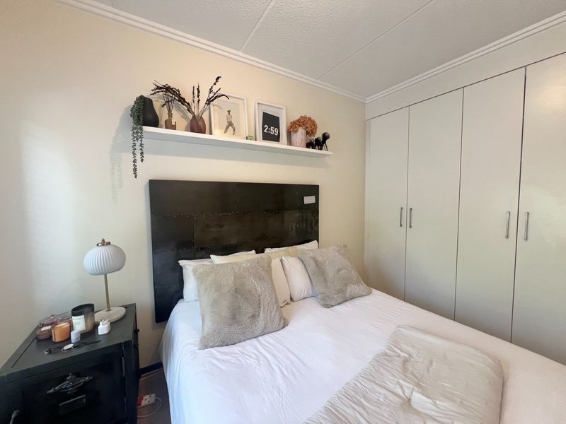 A well-maintained bedroom featuring built-in cupboards, a floating display shelf, and coved ceiling detailing.