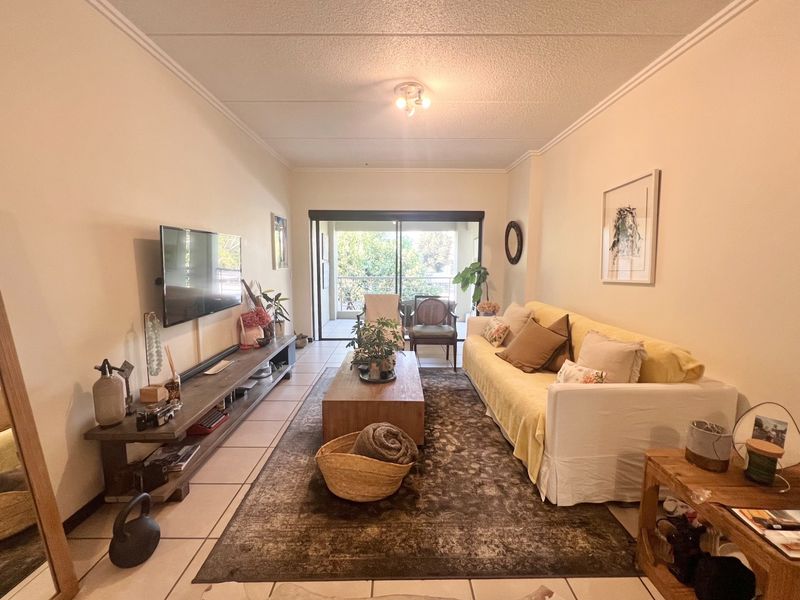 A comfortable living room featuring tiled flooring, coving, and a large sliding glass door that provides access to an outdoor balcony area.