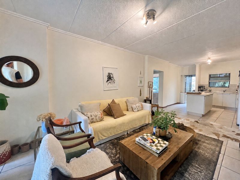 Open plan living area featuring tiled flooring and a functional kitchen with a central island, creating a connected and versatile living space.