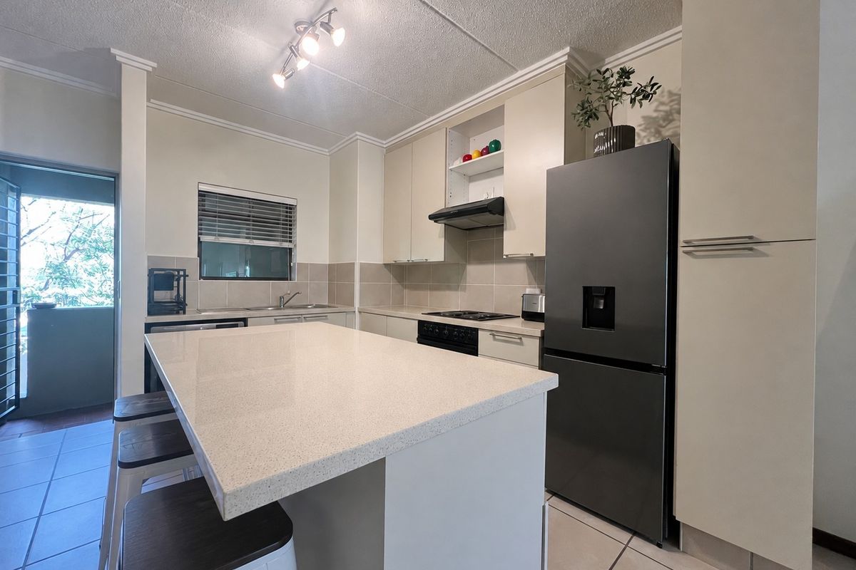 Modern kitchen featuring a central island with quartz countertops, built-in cabinetry, integrated appliances, and tiled flooring, offering a functional and clean cooking space.