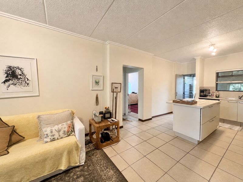 Open-plan living area featuring a kitchen with a central island, tiled flooring, and neutral finishes, providing a functional and connected layout.