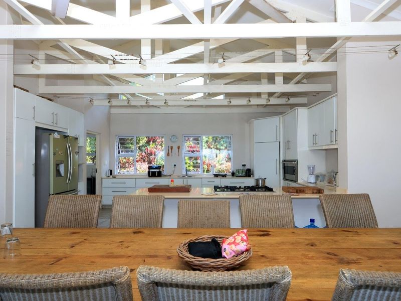Spacious open-plan kitchen and dining area featuring high exposed timber trusses, modern cabinetry, and a central island with a built-in gas hob.