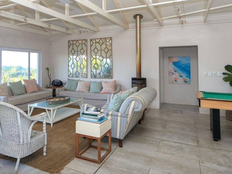 Spacious living area featuring exposed timber ceiling beams, a freestanding wood-burning fireplace, and large sliding glass doors providing natural light and outdoor access.