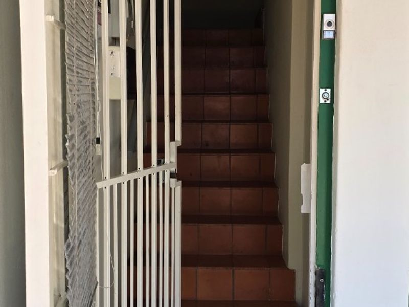 Entrance area featuring a security gate, tiled staircase leading upwards, and a transom window above the main door.