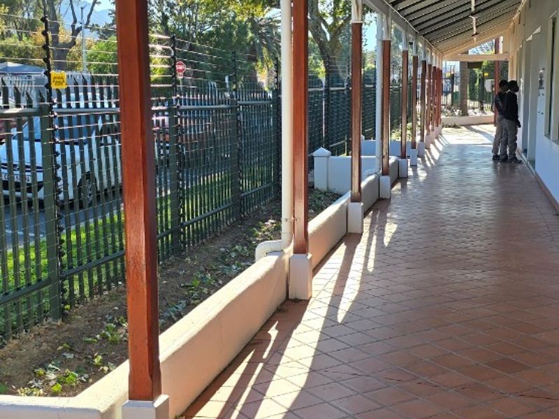 A covered outdoor veranda featuring tiled flooring, timber support posts, and a secure perimeter fence with integrated planter boxes.