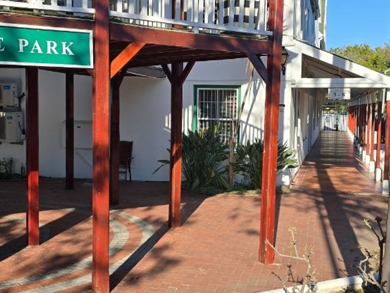 Exterior view of the property featuring a covered balcony with timber support posts and brick paved walkway.