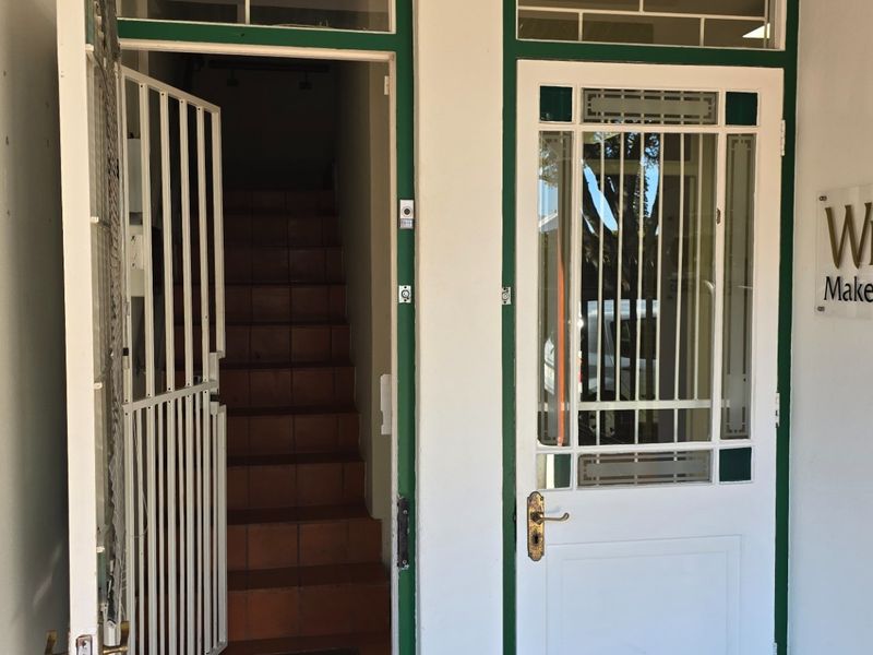 Entrance area featuring a security gate, tiled staircase, and a glass-panelled door with transom windows.
