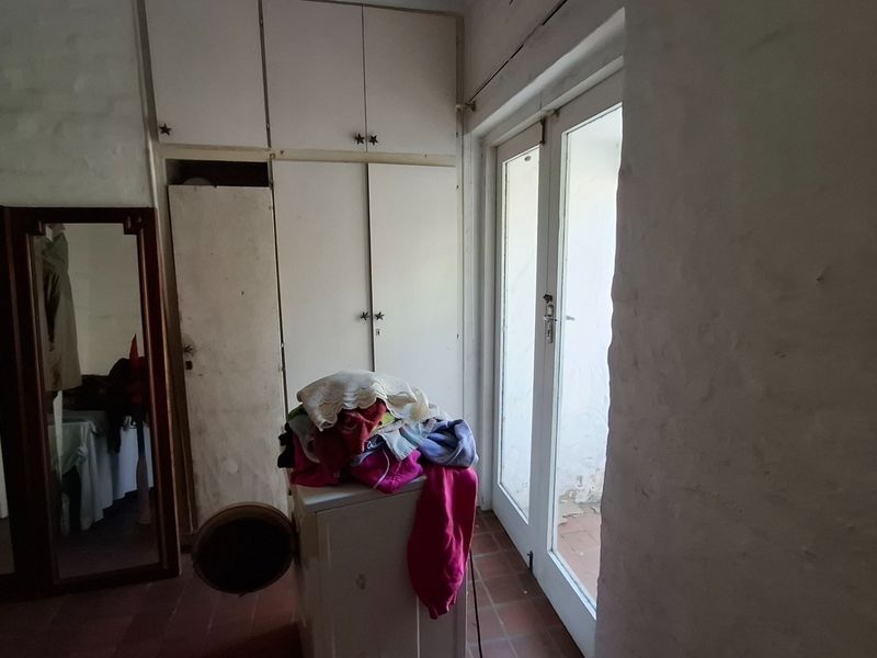 Bedroom featuring built-in cupboards and direct access to the exterior via glass french doors, requiring cosmetic updates to improve the overall finish.