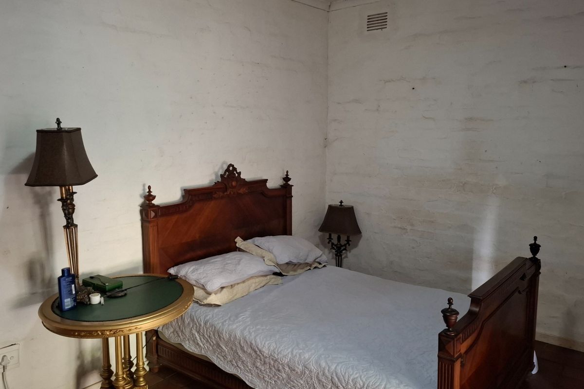 A bedroom featuring rustic, textured white walls and a ventilation grille, presenting an opportunity for cosmetic updates to improve the overall finish.