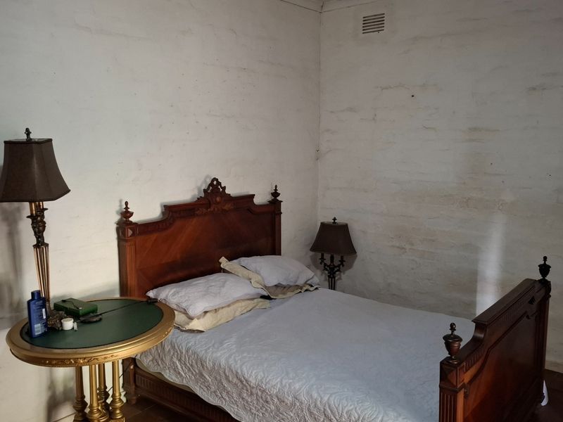 A bedroom featuring rustic, textured white walls and a ventilation grille, presenting an opportunity for cosmetic updates to improve the overall finish.