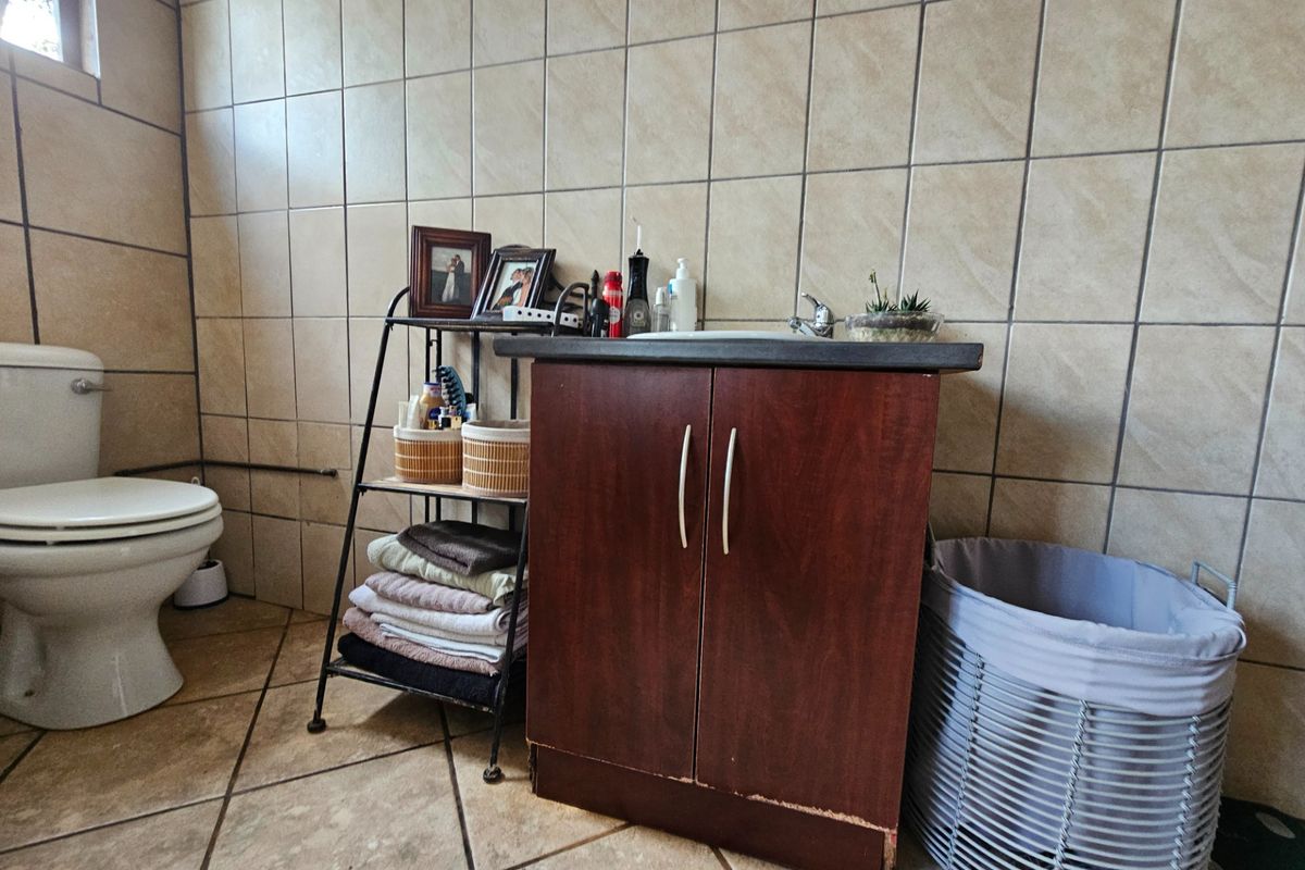 A functional bathroom featuring tiled walls and flooring, a vanity cabinet with a basin, and a standard toilet.