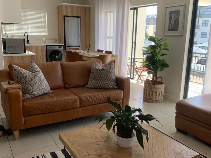 Modern open-plan living area featuring a functional kitchen with built-in cabinetry, tiled floors, and large sliding doors leading to a balcony.