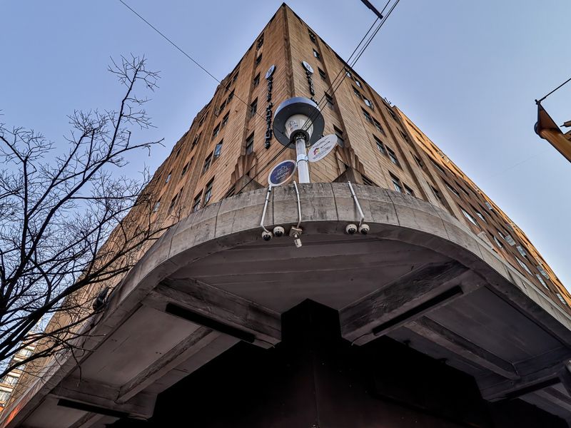 Low-angle view of a multi-story commercial building facade featuring a prominent concrete canopy and integrated security infrastructure.