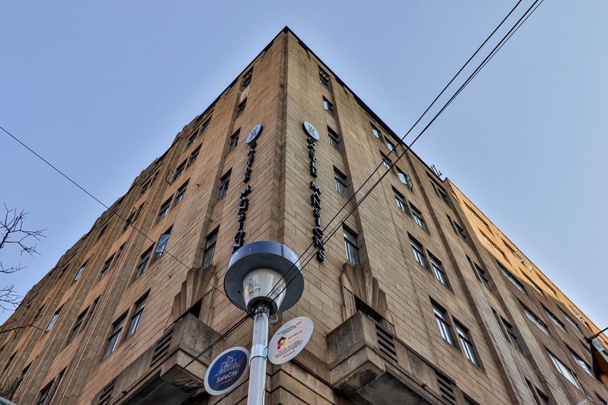 Low angle view of the Castle Mansions commercial building facade, showcasing its multi-story stone architecture and prominent corner signage.