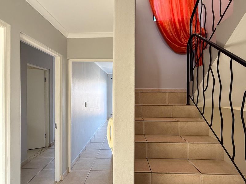 A bright hallway featuring tiled flooring and a staircase with a decorative wrought iron balustrade leading to the upper level.