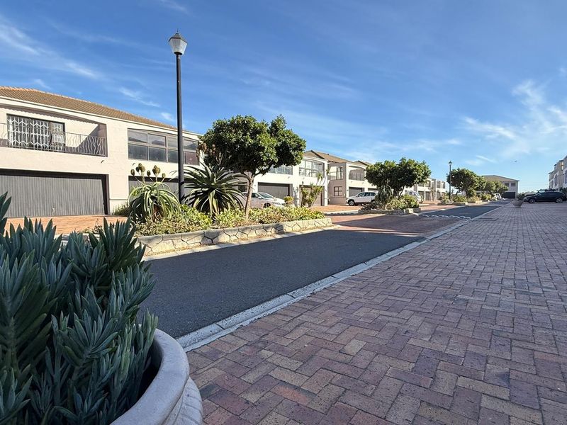 A view of the residential street featuring paved driveways, established landscaping, and access to multiple garage units.