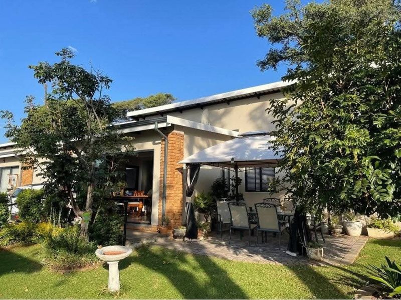 A well-maintained rear patio area featuring paved flooring, brick architectural detailing, and direct access to the interior through sliding glass doors.