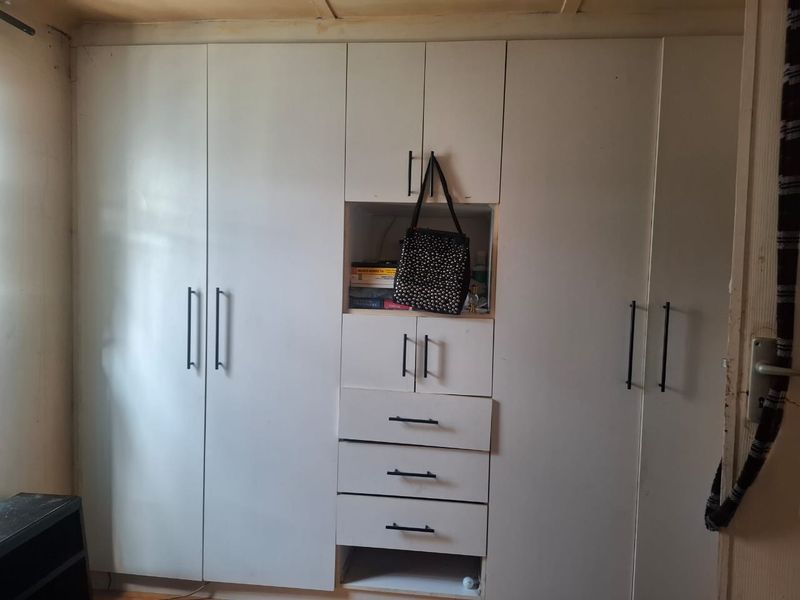 A bedroom featuring white built-in cupboards with modern black handles and integrated drawer storage.