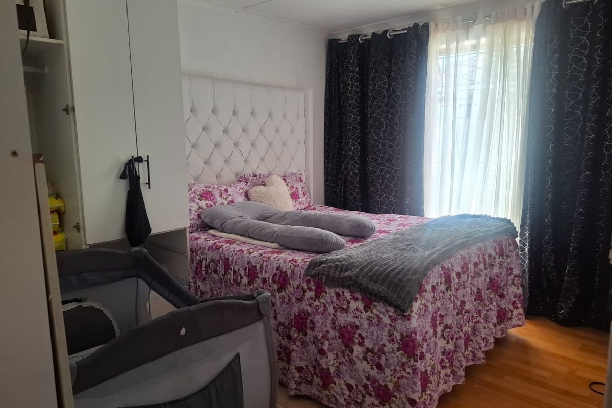 A functional bedroom featuring laminate flooring and a built-in wardrobe, providing essential storage space and a comfortable layout.