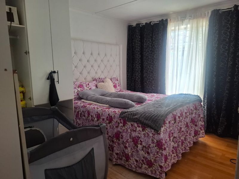 A functional bedroom featuring laminate flooring and a built-in wardrobe, providing essential storage space and a comfortable layout.