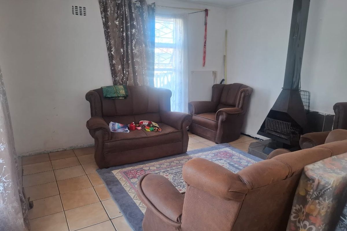 Living room featuring a freestanding fireplace and ceramic tiled flooring, offering a functional space with potential for cosmetic updates.