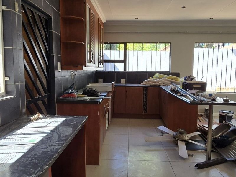 Spacious kitchen area featuring tiled flooring, dark cabinetry, and a tiled backsplash, currently in an unfinished state awaiting completion.
