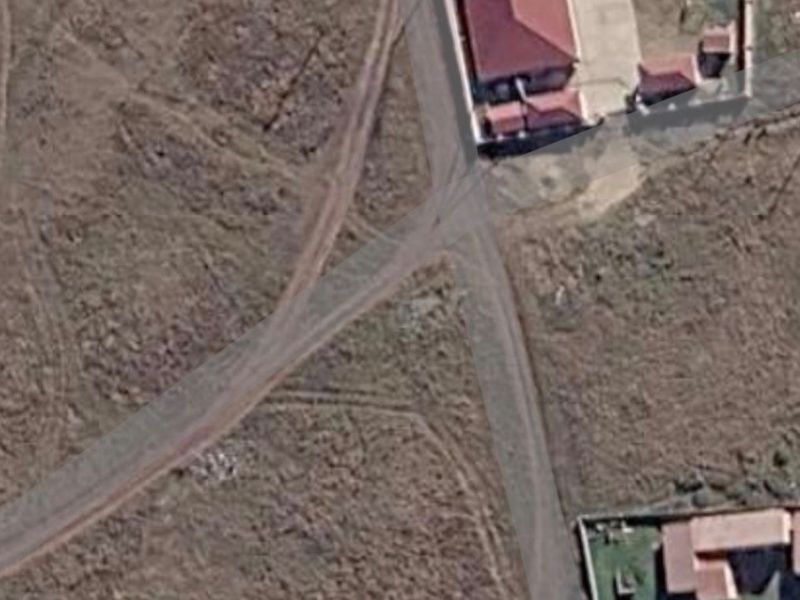 Aerial view of a vacant residential plot showing surrounding terrain and access roads.