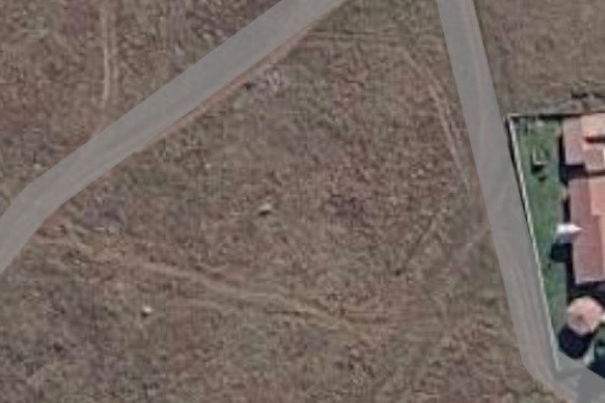 An aerial view of a vacant residential plot showing surrounding road infrastructure and neighboring properties.